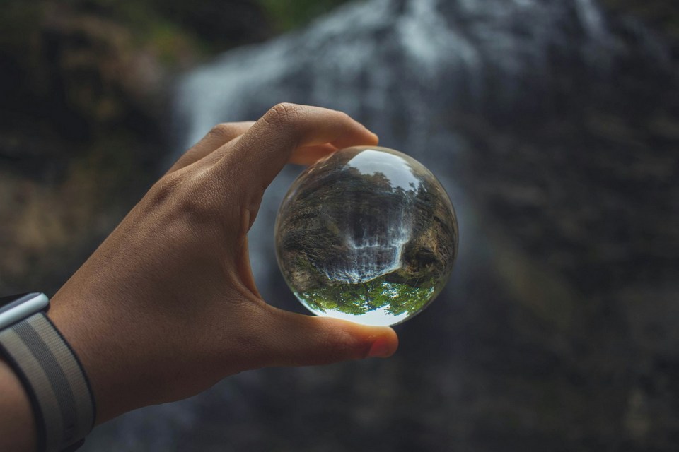 Hand holding a crystal ball reflecting a waterfall — how bookmakers discover and set opening prices
